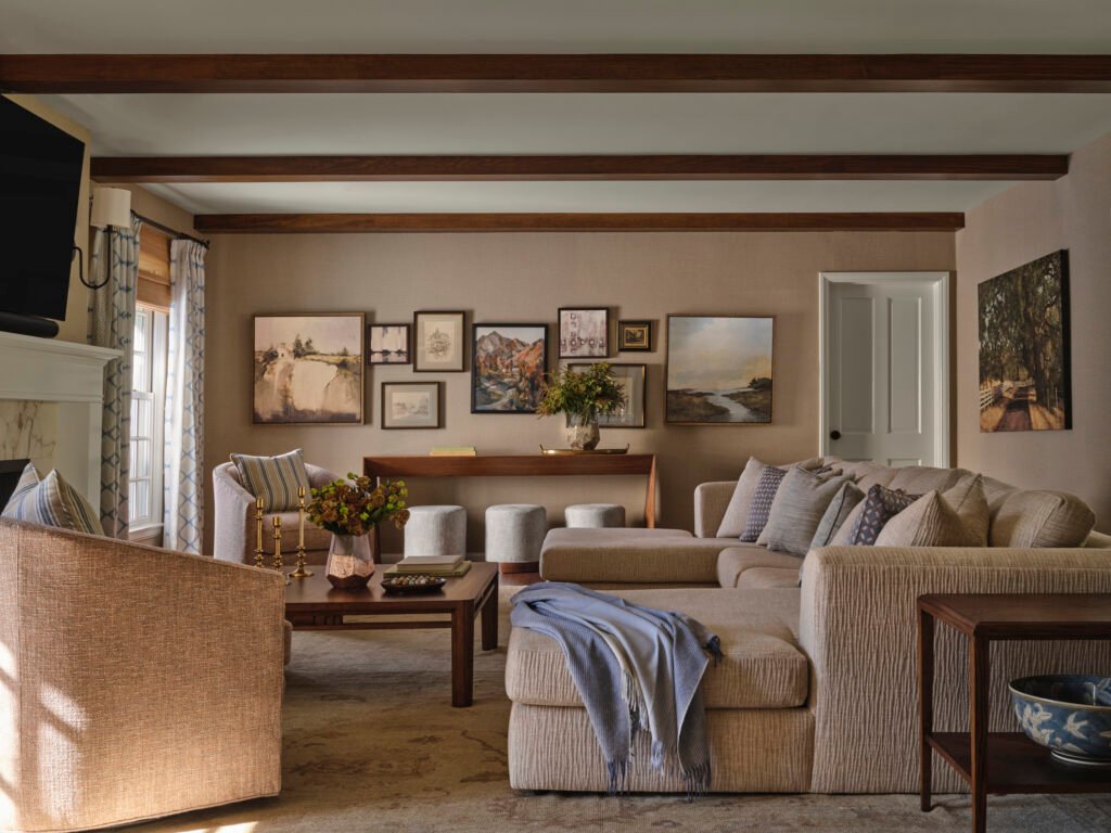 A beautifully furnished California ranch style home living room with a designer couch, multiple coffee tables, and striking wood furniture illuminated by morning light.
